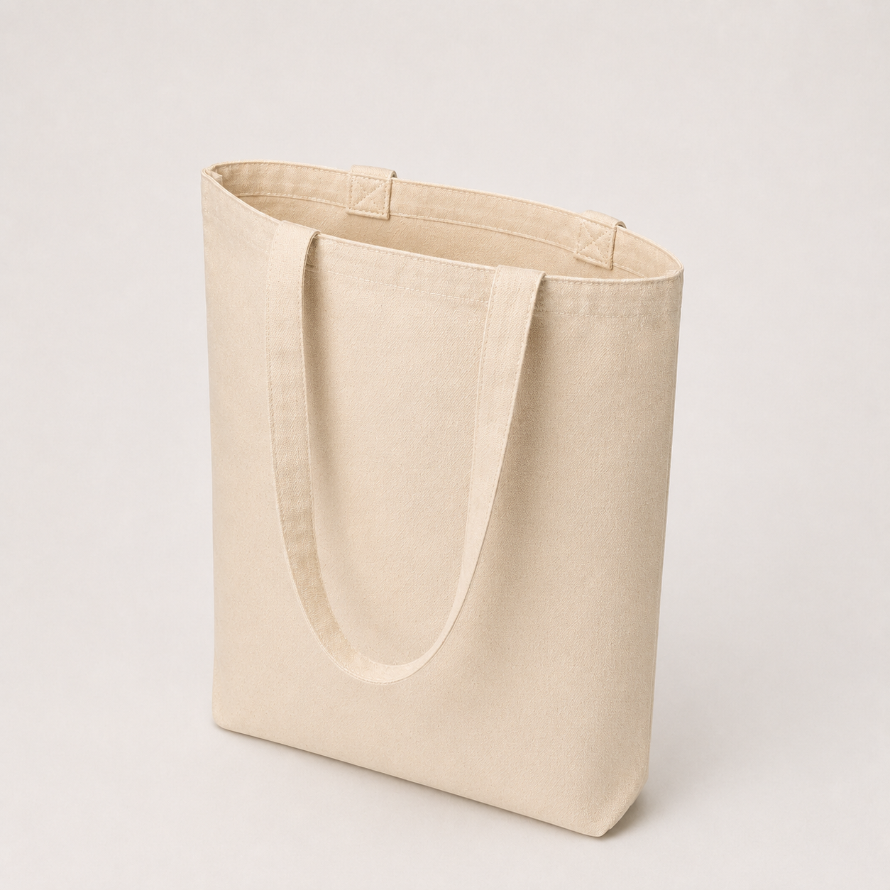 Open-top view of a natural cotton canvas tote bag showing its plain interior, top hem and handle attachments